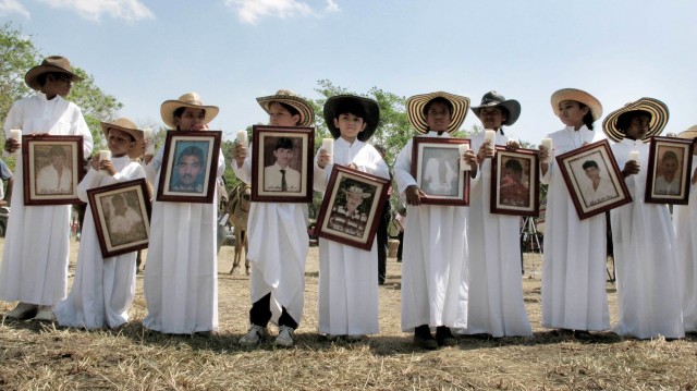 Niños de Las Brisas muestran fotos de sus familiares asesinados por los paramilitares. Foto por José Luis Rodríguez.